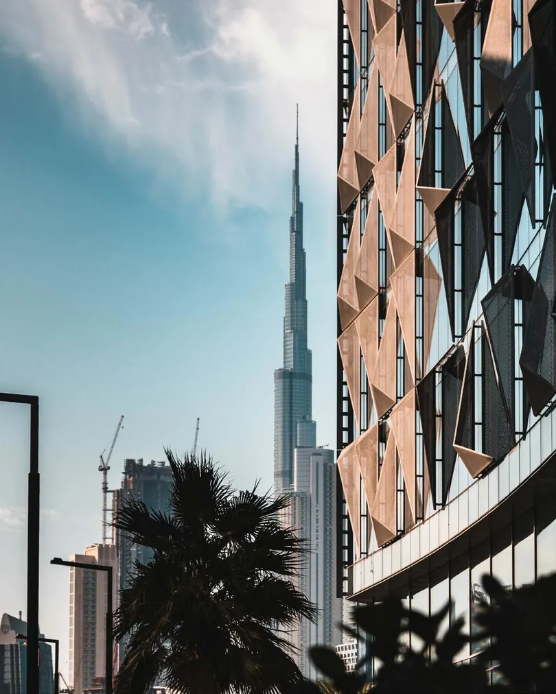 The faceted terracotta cladding of the tower with Burj Khalifa behind